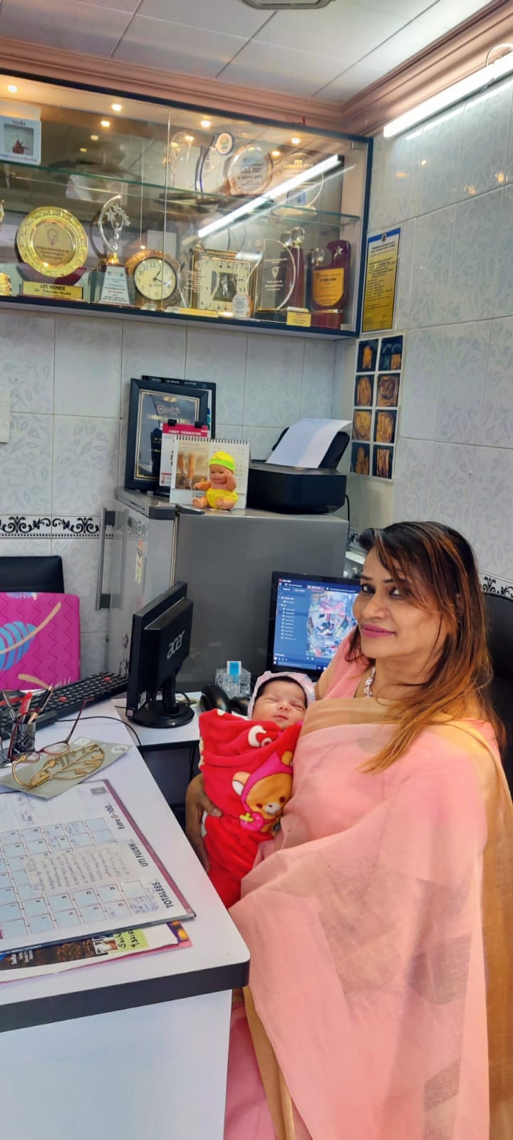 Dr. Fehmida Shaikh cradling newborn at the clinical ultrasound consultation desk
